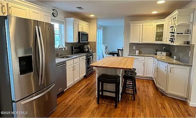 kitchen with stainless steel appliances, white cabinetry, sink, and butcher block countertops