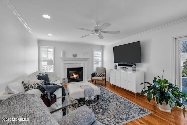 living room featuring crown molding, hardwood / wood-style flooring, a high end fireplace, and ceiling fan