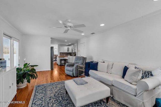 living room featuring ornamental molding, ceiling fan, and light wood-type flooring