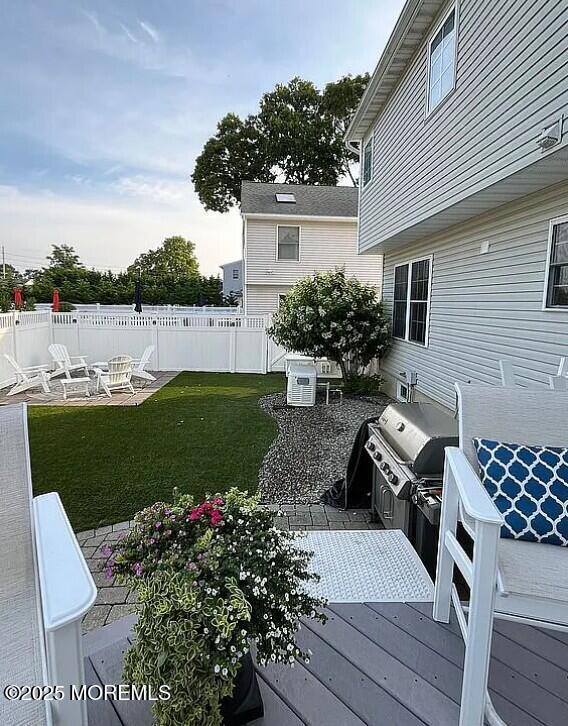 deck with area for grilling, a yard, grilling area, and an outdoor fire pit