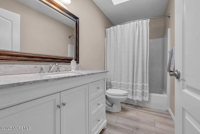 full bathroom featuring shower / bathtub combination with curtain, vanity, a skylight, and toilet