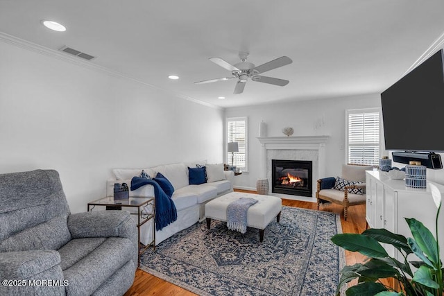 living room featuring crown molding, wood-type flooring, a high end fireplace, and a healthy amount of sunlight