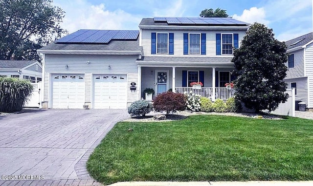 front of property featuring a garage, a front yard, solar panels, and covered porch