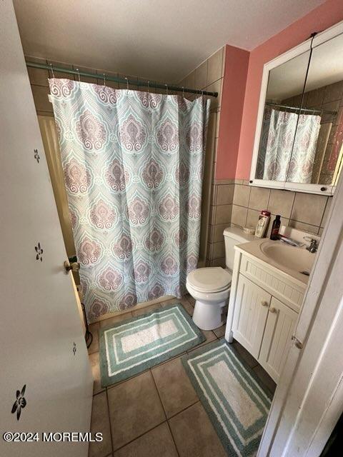 bathroom featuring tile walls, vanity, toilet, tile patterned floors, and a shower with curtain