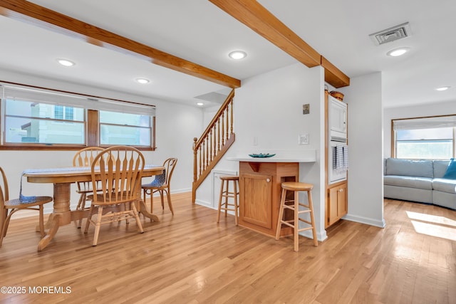 dining area featuring beam ceiling and light hardwood / wood-style flooring