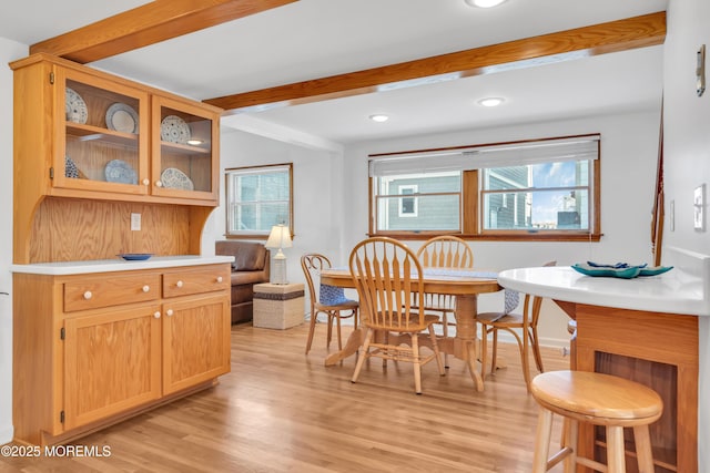 dining area featuring beam ceiling and light wood-type flooring