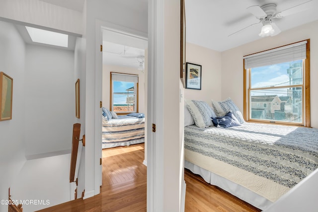 bedroom featuring a skylight, light hardwood / wood-style floors, and ceiling fan