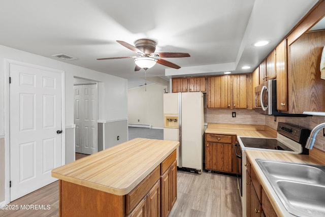 kitchen with stainless steel appliances, a center island, sink, and light hardwood / wood-style flooring