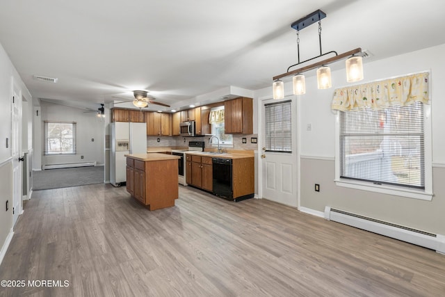 kitchen featuring sink, decorative light fixtures, a center island, a baseboard radiator, and appliances with stainless steel finishes