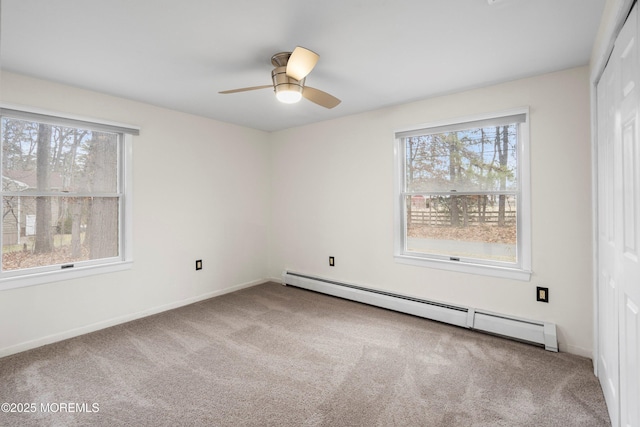 carpeted spare room featuring baseboard heating and ceiling fan