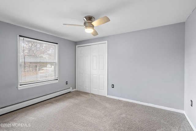 unfurnished bedroom with carpet, a baseboard heating unit, ceiling fan, and a closet