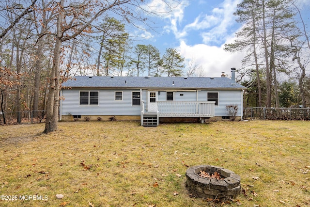 rear view of house with a wooden deck, a fire pit, and a yard