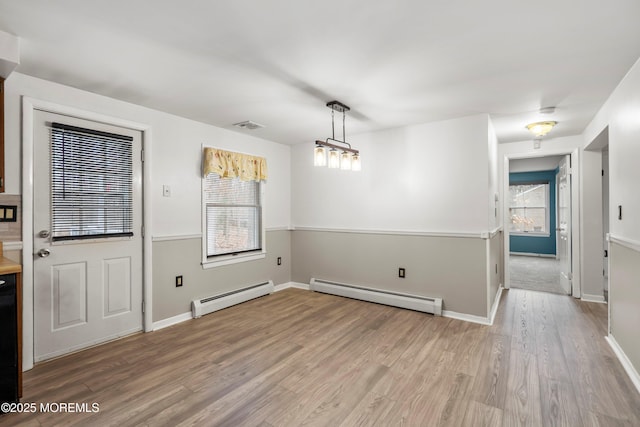 unfurnished dining area with a baseboard radiator and light wood-type flooring