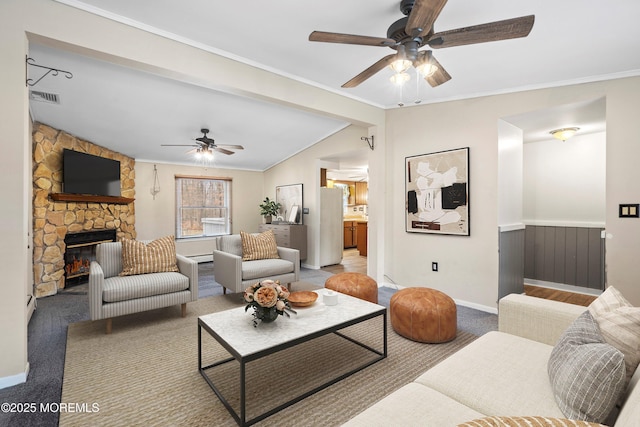 carpeted living room featuring crown molding, a stone fireplace, lofted ceiling, and ceiling fan