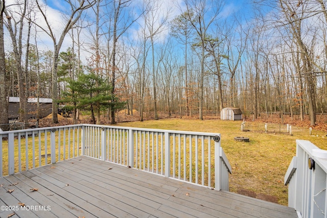 wooden deck featuring a fire pit, a lawn, and a storage unit