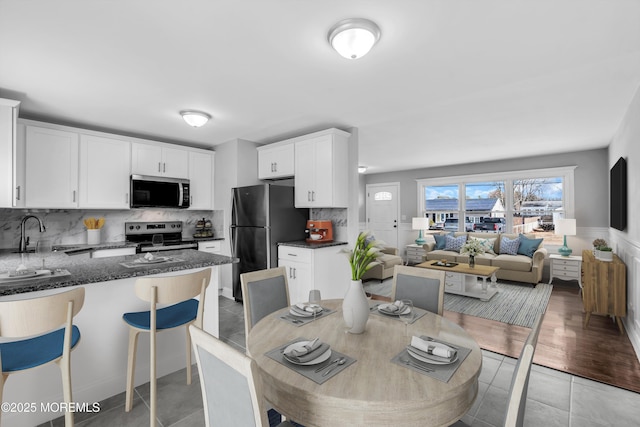 kitchen with sink, white cabinetry, tasteful backsplash, appliances with stainless steel finishes, and dark stone counters