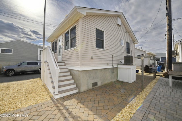 view of side of property featuring a patio and central AC