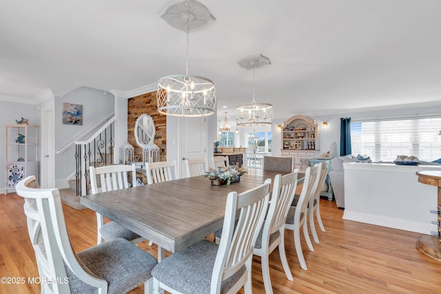 dining space with ornamental molding, a chandelier, and light hardwood / wood-style flooring