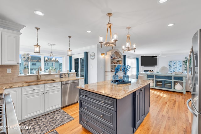 kitchen featuring pendant lighting, sink, stainless steel appliances, white cabinets, and a kitchen island