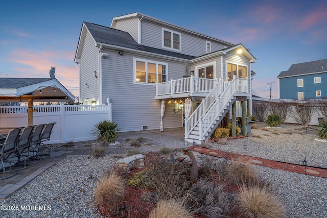 back house at dusk featuring a wooden deck and a sunroom