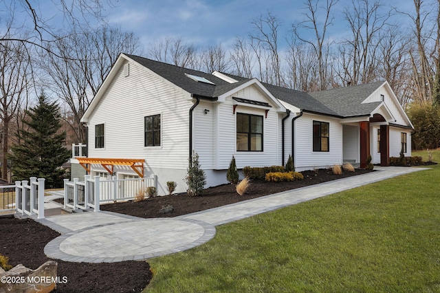 view of side of property with roof with shingles, a lawn, and a pergola