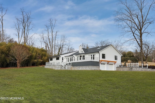 rear view of property with a lawn, a chimney, and an attached garage