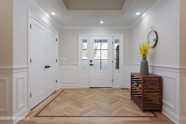 entrance foyer with crown molding, a tray ceiling, recessed lighting, and a decorative wall