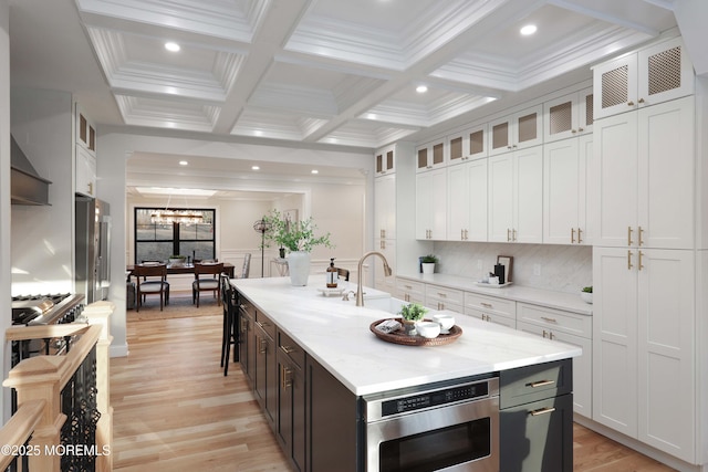 kitchen featuring a kitchen island with sink, glass insert cabinets, and white cabinets