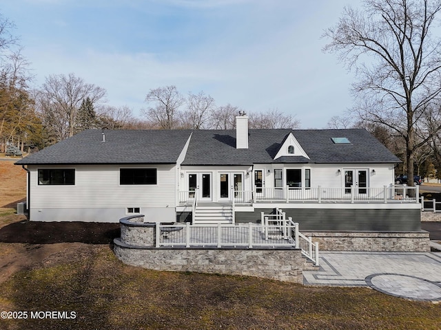 back of property with a shingled roof, a chimney, stairs, a deck, and french doors