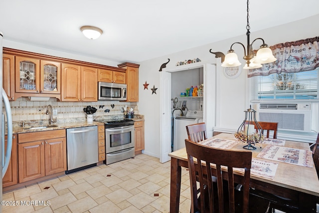 kitchen featuring pendant lighting, sink, stainless steel appliances, light stone counters, and tasteful backsplash