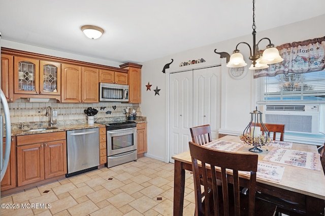 kitchen featuring sink, appliances with stainless steel finishes, light stone counters, tasteful backsplash, and decorative light fixtures