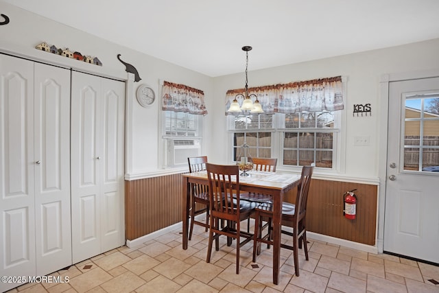 dining room with an inviting chandelier, wooden walls, and cooling unit