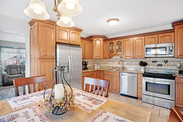 kitchen with decorative light fixtures, sink, decorative backsplash, stainless steel appliances, and light stone countertops