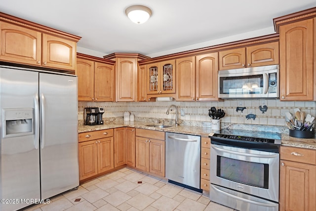 kitchen featuring light stone counters, appliances with stainless steel finishes, sink, and decorative backsplash