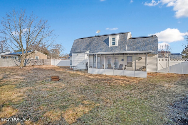 rear view of property featuring a sunroom and a lawn