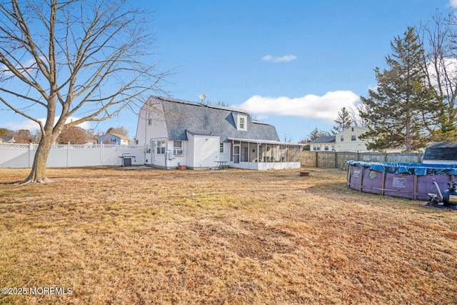 back of house with a yard, a covered pool, and a sunroom