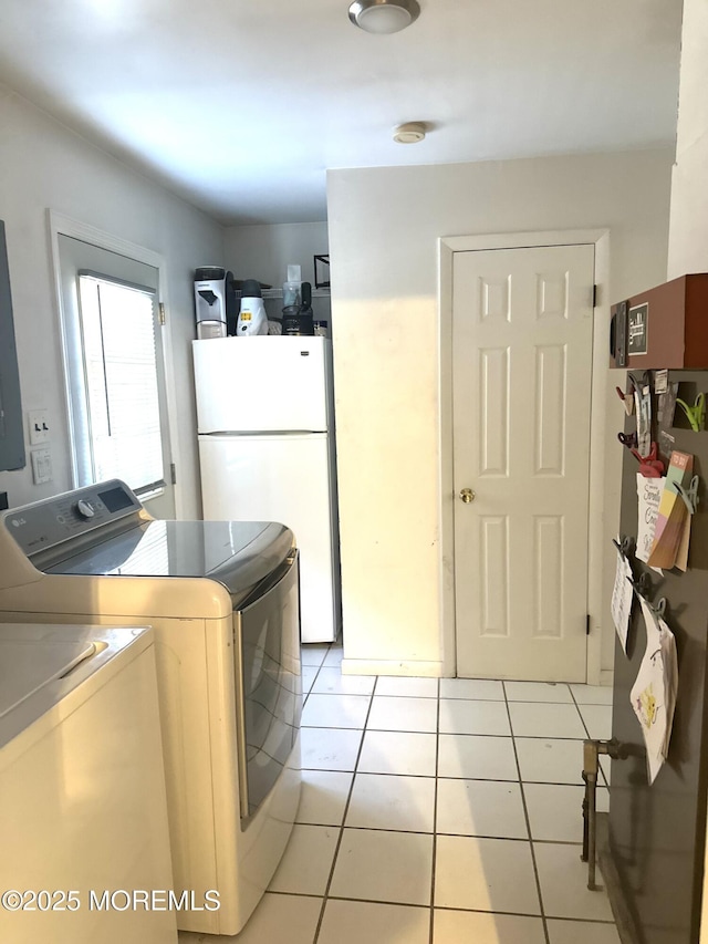 clothes washing area with separate washer and dryer and light tile patterned floors