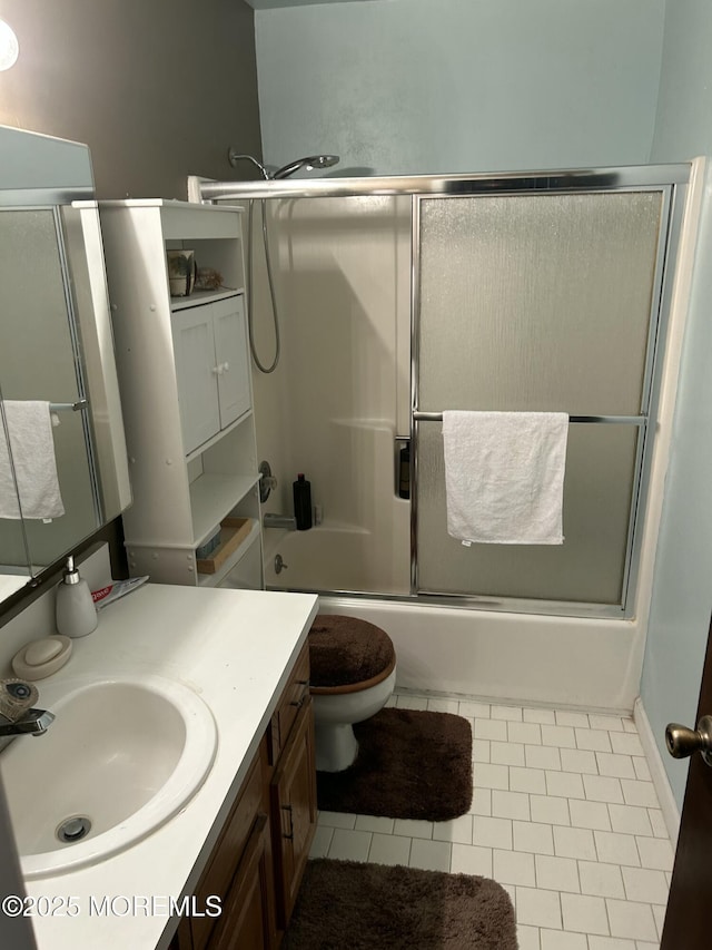 full bathroom featuring vanity, combined bath / shower with glass door, tile patterned floors, and toilet