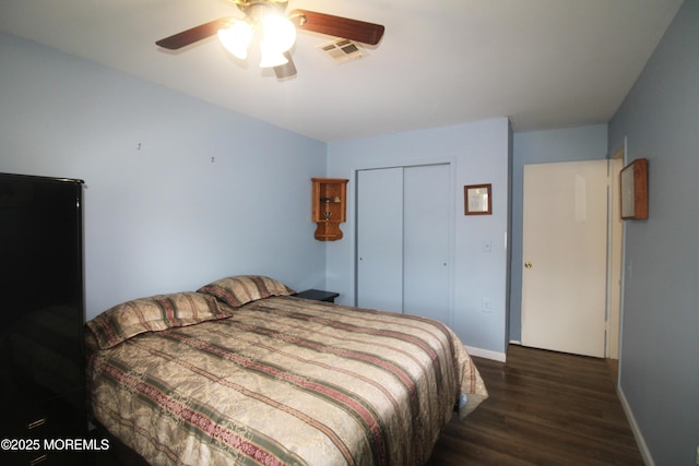 bedroom with a closet, dark hardwood / wood-style floors, and ceiling fan