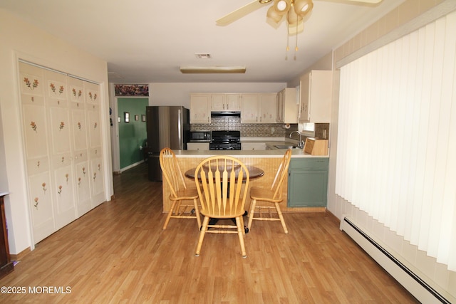 kitchen featuring a baseboard radiator, sink, a kitchen breakfast bar, stove, and kitchen peninsula