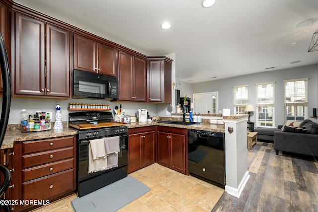 kitchen with sink, black appliances, kitchen peninsula, and light stone countertops