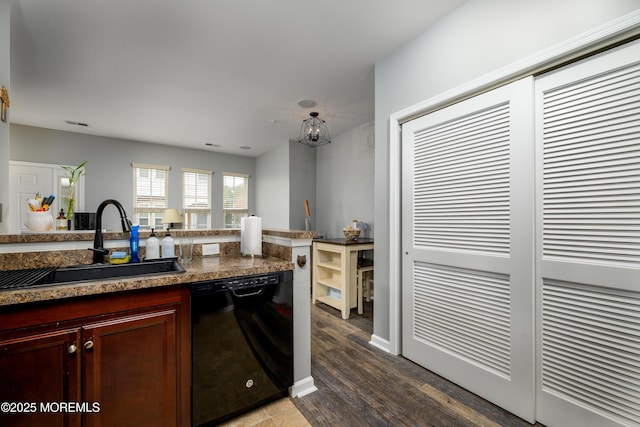 kitchen with wood-type flooring, black dishwasher, sink, and dark stone counters