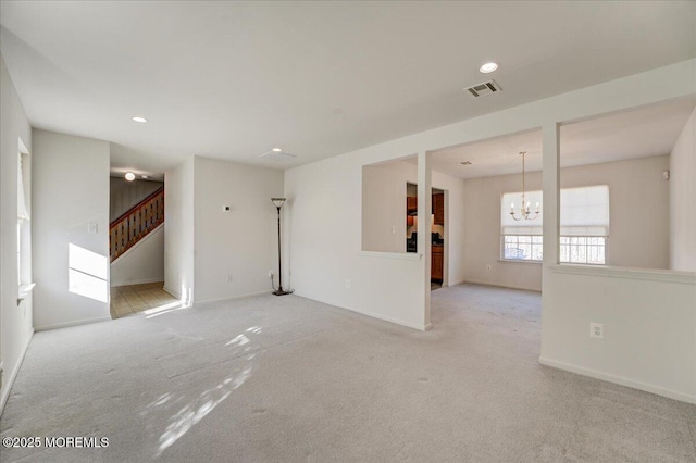 spare room with a notable chandelier and light colored carpet