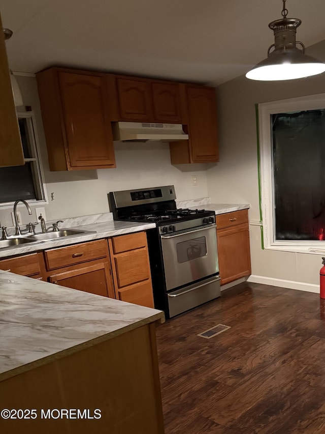 kitchen with gas range, dark hardwood / wood-style flooring, sink, and pendant lighting