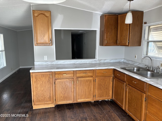 kitchen with pendant lighting, sink, dark hardwood / wood-style flooring, ornamental molding, and kitchen peninsula