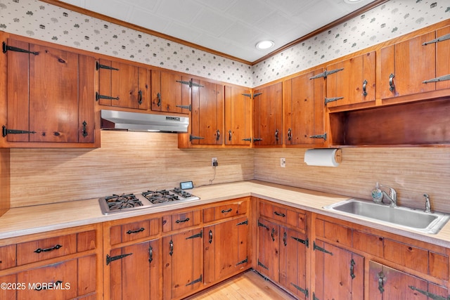 kitchen featuring sink, ornamental molding, light hardwood / wood-style floors, stainless steel gas cooktop, and decorative backsplash