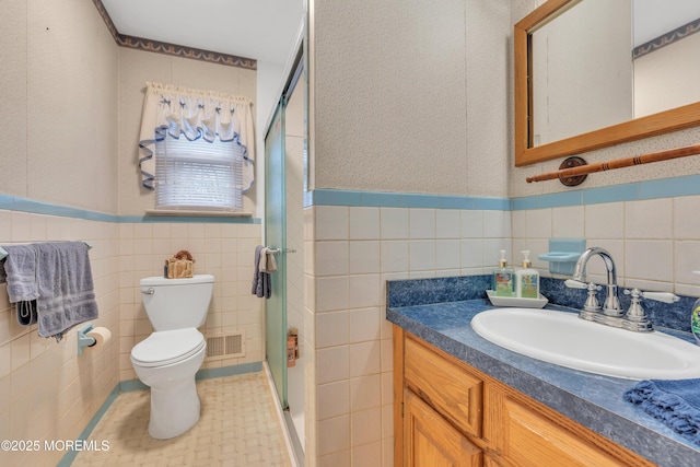 bathroom with vanity, toilet, tile walls, and walk in shower