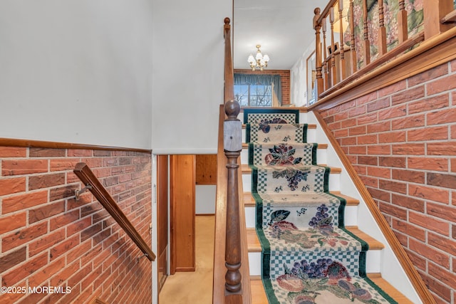 stairway with brick wall and a chandelier