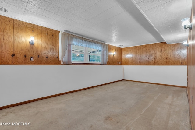 carpeted spare room featuring wooden walls