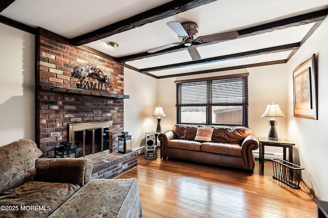 living room with beam ceiling, baseboard heating, ceiling fan, light hardwood / wood-style floors, and a brick fireplace